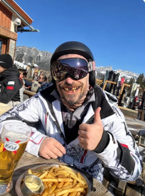 Skier wearing a printed ski mask at an outdoor lunch table